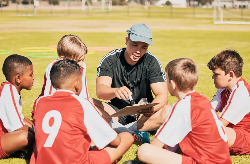 Coach reviewing the roster on a clipboard with a youth soccer team