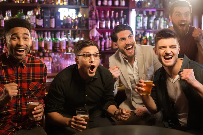 Friends cheering together while watching at a pub