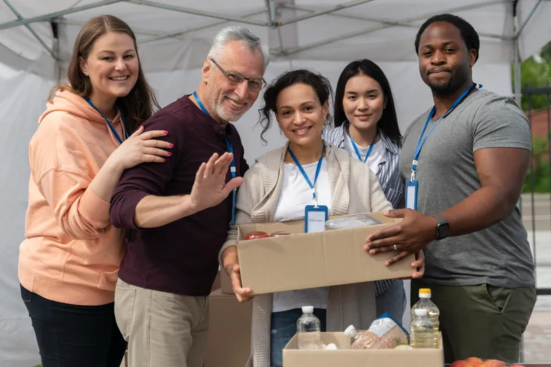 Volunteers greeting people at a donation booth under an event tent
